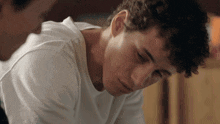 a man with curly hair is looking down at something