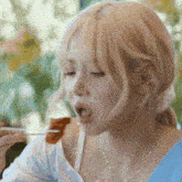 a blonde woman is eating a piece of food with a fork
