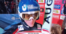 a person wearing a helmet and goggles with the words new hill record on the bottom