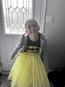 a young girl wearing a batman shirt and a yellow skirt