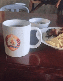 a mug with a picture of a man on it sits on a table next to plates of food