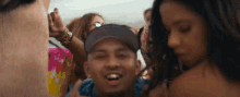 a group of people are standing around a man wearing a hat .