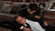two men are fighting in a living room with a picture of a man on a table