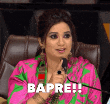a woman in a pink and green dress is pointing at a microphone and says bapre !!