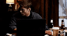 a man is sitting at a table with a laptop .