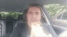 a man is eating a sandwich while sitting in a car
