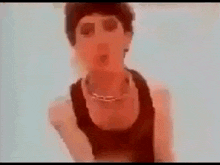 a man in a black tank top is giving the middle finger to the camera .