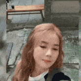 a woman with red hair is taking a selfie in front of a wooden bench