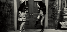 a couple of women are dancing in front of a door .