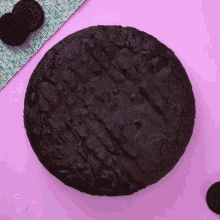 a chocolate cookie is sitting on a pink surface next to some oreos