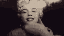 a black and white photo of marilyn monroe with her eyes closed and a man touching her face .