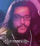 a man with long hair and a beard is wearing glasses and earbuds
