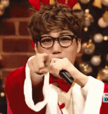 a man wearing glasses and a santa costume is pointing at the camera