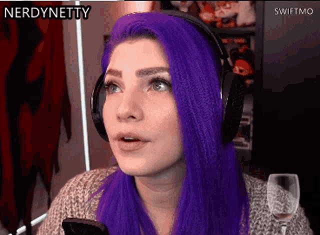 a woman with purple hair is wearing headphones and looking at her phone ..