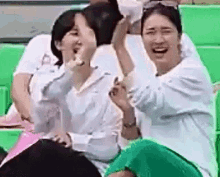 a group of women are sitting in a stadium laughing and clapping .