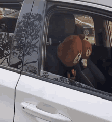 a white car with two brown teddy bear headrest covers