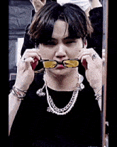 a young man wearing a pearl necklace and sunglasses makes a face