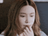 a close up of a woman 's face with her hand on her face