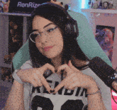 a girl wearing glasses and headphones making a heart shape with her hands in front of a sign that says renrize