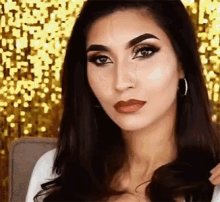 a woman wearing hoop earrings and a white shirt looks at the camera
