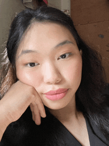 a woman with a hand on her face looks at the camera