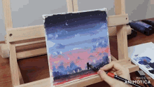 a person is painting a sunset on a canvas on an easel .
