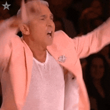a man wearing a pink jacket and a white shirt with his arms in the air .