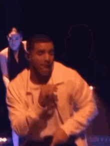 a man is singing into a microphone on a stage with a woman behind him .