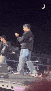 a man is standing on a stage holding a microphone while another man stands behind him .
