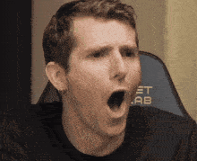 a man with his mouth open is sitting in front of a chair that says et lab