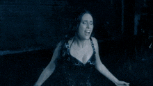 a woman in a plunging black top is standing in the rain