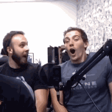 two men are standing in front of a microphone .