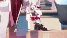 a person wearing a pair of black shoes with a pink bow on the side