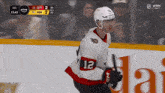 a hockey player with the number 12 on his jersey stands on the ice