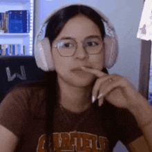 a woman wearing headphones and glasses is sitting in front of a computer screen .