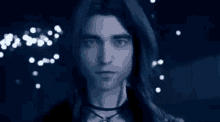 a man with long hair and a choker is looking at the camera in a blurry photo .