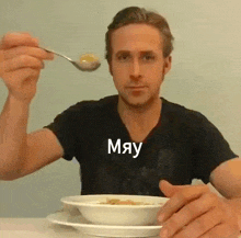 a man is sitting at a table with a bowl of soup and a spoon in his hand ..