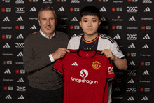 a man and a boy are holding a snapdragon jersey