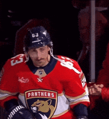 a man wearing a red panthers jersey looks down