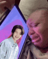 a person is crying while looking at a picture of a man on a tablet .