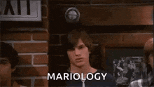 a man is standing in front of a brick wall with the word mariology written on it