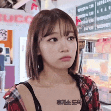 a girl in a plaid shirt is standing in front of a sign that says ' gucci ' on it