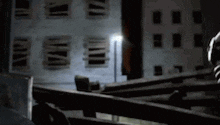a person is standing in front of a building at night holding a gun .