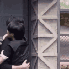 a couple of men are hugging each other in front of a wall .