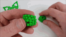 a person is holding a bunch of green beads in their hand