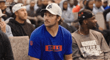 a man in a bills shirt sits in a crowd of people