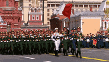 a group of soldiers marching in front of a building that says 100 on it