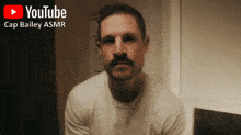 a man with a mustache is sitting in front of a youtube sign