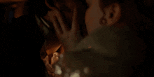 a man and woman are kissing in a dark room in a close up of their faces .