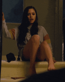 a woman is sitting on the edge of a bathtub